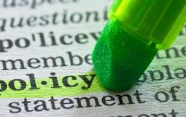 green highlighter pen over word policy in a dictionary